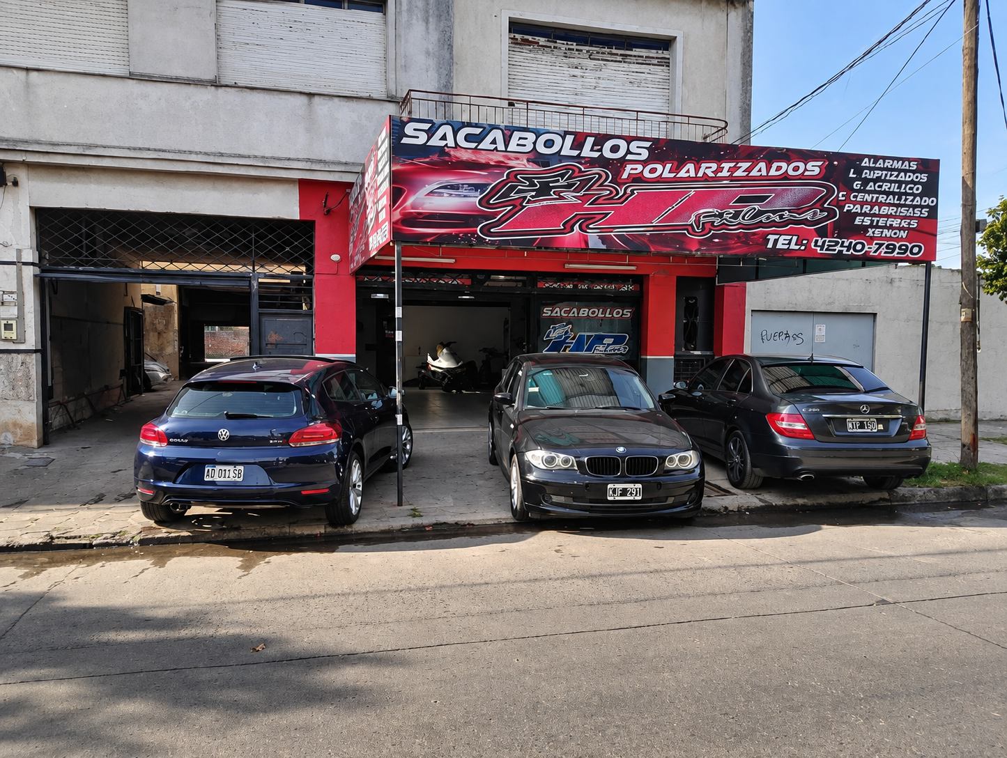 Frente del local HP Film con autos de clientes